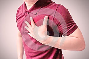 An adult man uses his hand to hold his chest.