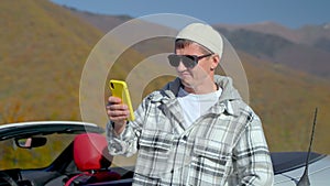 adult man using smartphone in mountain, connecting to mobile net during travelling across country