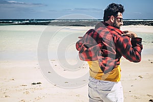 Adult man viewed from back enjoying the beach and the nature with strong wind - tropical travel destination for travelers and
