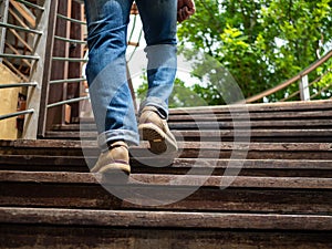 Adult man walking up the wooden stairs. Moving forward concept.