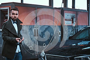 Adult man washing his car outdoors in a carwash under high pressured water