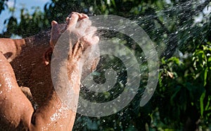 Adult man is washing in the summer garden