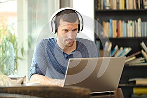 Adult man wearing headphones using a laptop