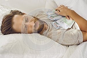 Adult man who is worried about his money sleeps with dollar banknotes in his hands