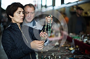 Adult man and woman are looking antiquariat at the market of old things