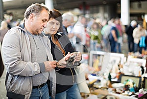 Adult man and woman are looking antiquariat at the market of old things