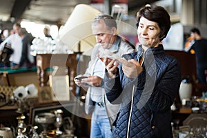 Adult man and woman are looking antiquariat at the market of old things
