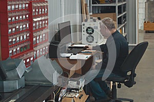 Adult man working at the computer at factory of production CNC machine with lathes