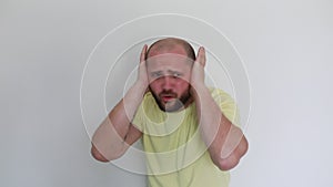 Adult Man in Yellow Shirt Expressing Frustration With Hands on Ears Indoors