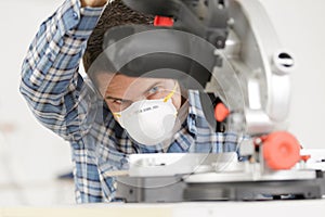 Adult master sawing platband with circular saw indoors