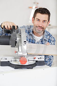 adult master sawing platband with circular saw indoors