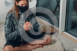 Adult mature woman doing yoga in face mask at home living room with smoking palo santo stick tree photo