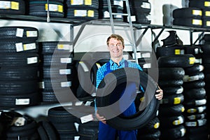 Adult mechanic man standing with new car tires