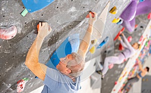 Adult man practicing rock climbing on climbing wall