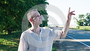 Adult middle-aged man on the road. Cheerful man points a finger up