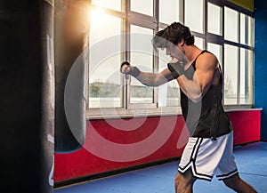 Adult muscular man boxing with punching bag