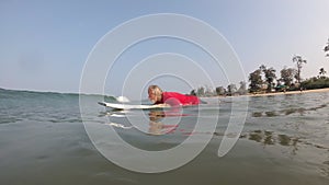 An adult old man is surfing in the sea. The concept of active life in old age.