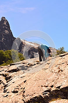 Adult person is doing exercise on a steep rocky mountain peak