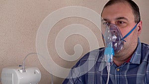 Adult person makes inhalations with the help of nebulizer. patient breathes through an Oxygen Mask.