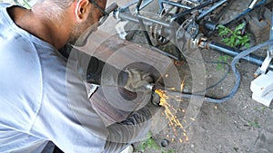 Adult repairman or mechanic grinding metal using circular saw. Worker cutting some detail in garage or workshop. Man