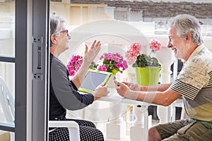 Adult senior couple use laptop outdoor leisure activity at the terrace at home. smile and enjoy the nice weather and the retired