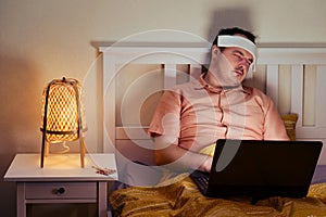 Adult sick man sleeping tiredly lying on bed with computer photo