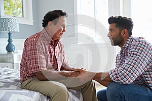 Adult Son Comforting Father Suffering With Dementia photo