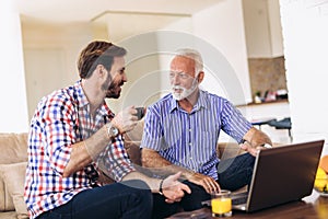 Adult Son Helping Senior Father With Computer