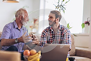 Adult Son Helping Senior Father With Computer