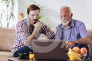 Adult Son Helping Senior Father With Computer