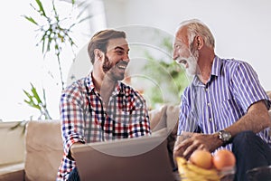 Adult Son Helping Senior Father With Computer