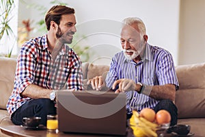 Adult Son Helping Senior Father With Computer