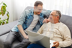 Adult Son Helping Senior Father With Computer At Home