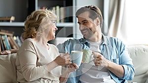 Adult son visit older mother drinking tea enjoy pleasant talk