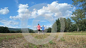 Adult sports heterosexual couple running hand in hand in autumn nature. Love sports activities together.