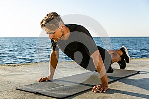 adult sportsman with wireless earphones doing push ups