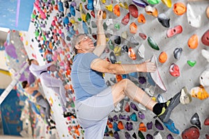 Adult man practicing rock climbing on climbing wall