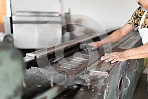 An adult tortilla maker is the conveyor belt of the nixtamal mill to prepare corn tortillas