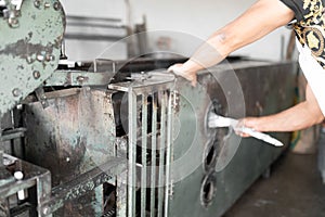 An adult tortilla maker is turning on the gas stove of the nixtamal mill to prepare corn tortillas