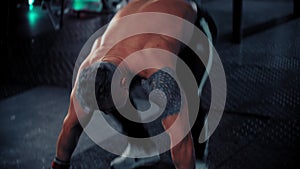 An adult tough man bodybuilder with tattoo on the shoulder doing endurance exercises