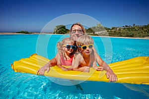 Adult and two children on a large yellow inflatable pool float