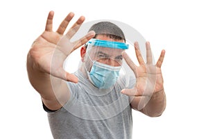 Adult wearing mask and face shield making stay away gesture