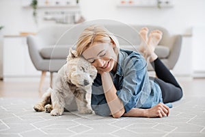 Adult and Westie snuggling with heads while staying on floor