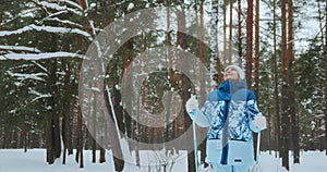 An adult woman of 60 years old walks in a winter park outdoors on skis