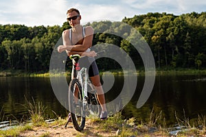 An adult woman on a bicycle, on the shore of a lake