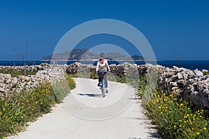 Adult woman is biking at Favignana Island, Italy photo