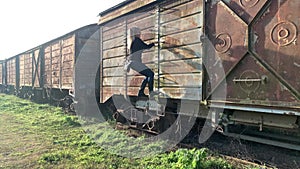 Adult woman climbing the side ladder of an abandoned train freight car. Abandoned places concept