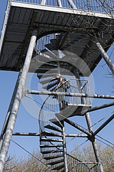 Adult woman clinbing down the stairs of a metal watchtower