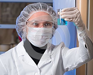 Adult woman closeup protective glasses and medical mask holding in his hand glass flask