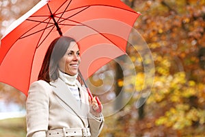 Adult woman contemplating autumn under red umbrella